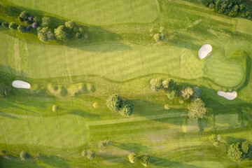 Aerial view of links golf course during summer showing green and bunkers at driving range - Powered by Adobe