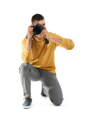 Young professional photographer taking picture on white background