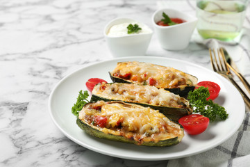 Baked stuffed zucchinis served on white marble table