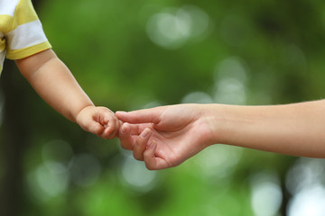 Mother with her baby holding hands together in park on summer day