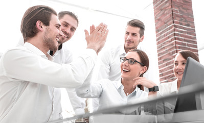 employees give each other a high five sitting at the Desk