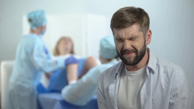 Husband hardly breathing while wife pushing to give child birth on background