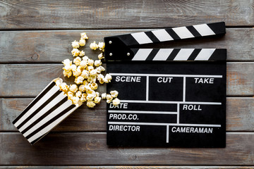 Go to the cinema with popcorn and clapperboard on wooden background top view