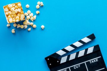 Filmmaker profession with clapperboard and popcorn on blue background top view copyspace
