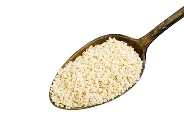 White sesame in a spoon isolated on a white background. Spice on isolate. View from above.