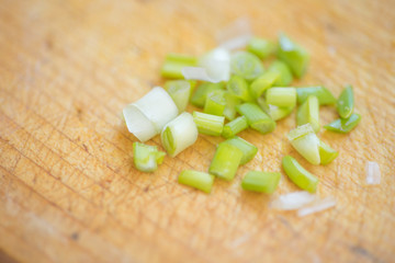 Cut green onion on the brown wooden board.