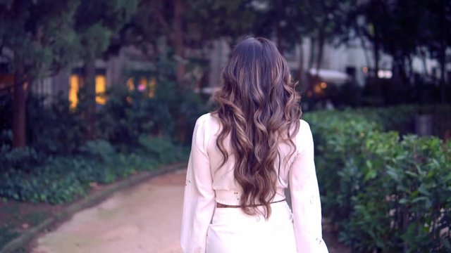 Beautiful Asian girl walking in the park. She is wearing white dress. Happy video