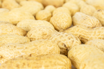 Lot of whole natural yellow peanut in closeup isolated on white background