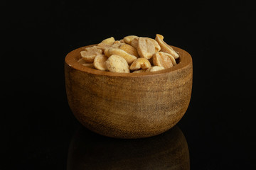 Lot of halves of natural yellow peanut in tiny wooden bowl isolated on black glass
