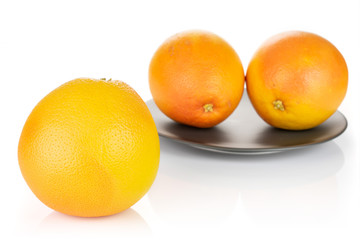 Group of three whole fresh pink grapefruit on gray ceramic plate isolated on white background