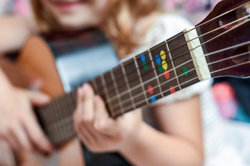 Fototapeta premium Girl learns to play guitar during a music lesson on the instrument