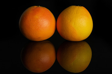 Group of two whole fresh pink grapefruit isolated on black glass