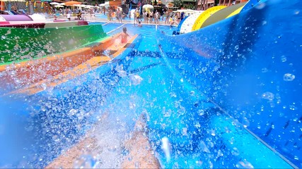 Man having fun on a water slide. Cool people having fun on the water slide in the aqua fun park glides playing happy and water splashes are all over.