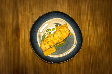 plate of roasted salmon with ravioli, gratin cheese and dill