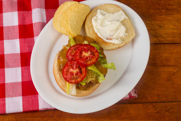 Overhead View of Homemade Cheeseburger with Lettuce and Juicy Tomato on Country Kitchen BG