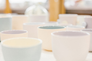Fototapeta na wymiar Set of multicoloured ceramic minimalistic vase and cups on soft background.