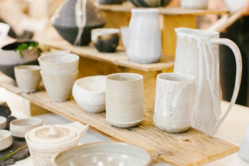 Set of gray ceramic minimalistic vase and cups on soft warm background.