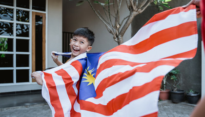 happy malaysian kid run around the house carrying malaysia flag