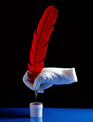 A white glove holding a red feather Quill ink pen
