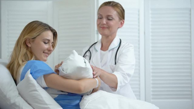 Smiling doctor giving happy mother newborn child, happy motherhood, family