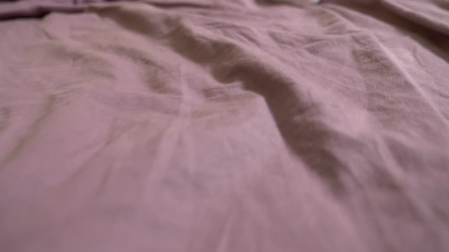 white female vibrator on crumpled lilac sheets.