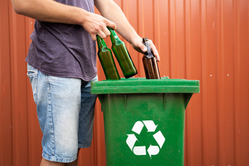 Man putting glass bottles in recycle bin 