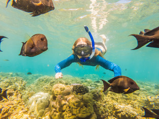 Happy woman in snorkeling mask dive underwater with tropical fishes in coral reef sea pool. Travel...