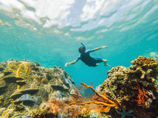 Happy man in snorkeling mask dive underwater with tropical fishes in coral reef sea pool. Travel lifestyle, water sport outdoor adventure, swimming lessons on summer beach holiday. Aerial view from