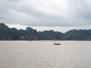 Fototapeta na wymiar Fishing boats on the water in Ha Long Bay, Vietnam, with limestone rocks behind