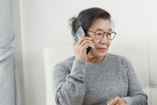 Asian senior woman make a phone call white sitting on sofa at home, lifestyle concept.