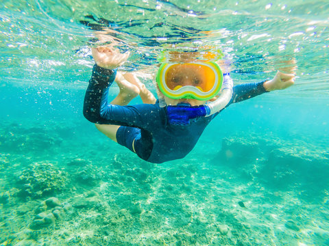 Happy family - active kid in snorkeling mask dive underwater, see tropical fish in coral reef sea pool. Travel adventure, swimming activity on summer beach vacation with child