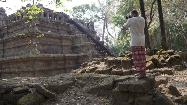 Man taking photos, sightseeing ancient Angkor Wat temple ruins in Cambodia