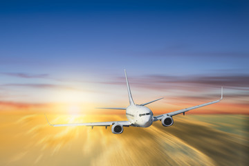 White airplane flying above cloud at sunset