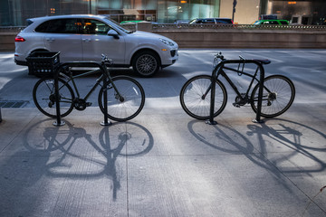 Two locked bikes cast shadows on the sidewalk of Wacker Dr.
