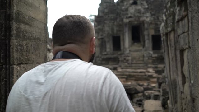 Man taking photos, sightseeing ancient Angkor Wat temple ruins in Cambodia