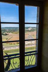 View through a chateau window over the French countryside towards the medieval village of Beynac-et-Cazenac