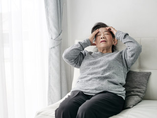 Asian senior woman having headache at home, health care concept.