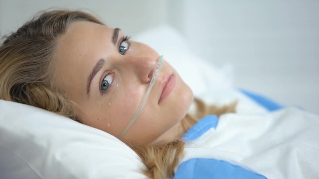 Crying lady with oxygen nasal cannula looking at camera, worrying before surgery