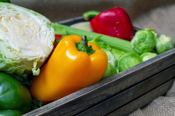 Various non-toxic fresh vegetables are placed in a wooden box placed on a mat. Many vegetables are purple and green sprouts, red pepper Yellow and green, Corn and others