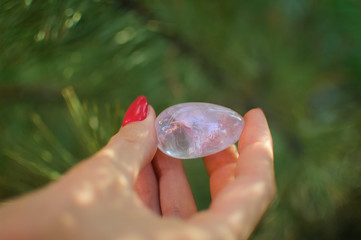 Female hand with red manicure holding transparent violet amethyst yoni egg for vumfit, imbuilding...