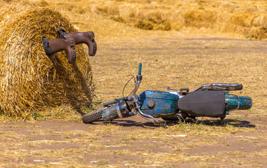 A motorycle near the haystack and boots in the pile of straw. crash humor concept decoration
