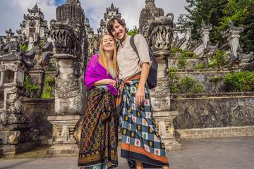 Fototapeta na wymiar Happy couple of tourists on background of Three stone ladders in beautiful Pura Lempuyang Luhur temple. Summer landscape with stairs to temple. Paduraksa portals marking entrance to middle sanctum