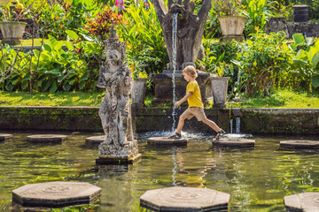 Boy tourist in Taman Tirtagangga, Water palace, Water park, Bali Indonesia. Traveling with children concept. Kids friendly place