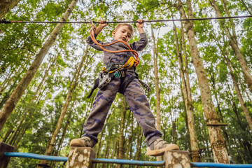 Little boy in a rope park. Active physical recreation of the child in the fresh air in the park. Training for children