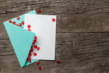 Love letter with red hearts. Blank template with place for text on postcard. Green envelope on old wooden background. mock-up