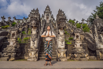 Young man tourist on background ofThree stone ladders in beautiful Pura Lempuyang Luhur temple. Summer landscape with stairs to temple. Paduraksa portals marking entrance to middle sanctum jaba tengah