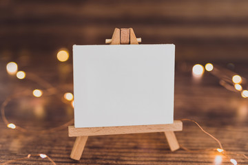 black canvas miniature surrounded by fairy lights on wooden desk with copyspace