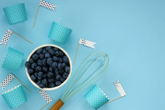 Blueberry Berry Muffins. Berry Baking. Blueberries In A  Cup, Blue Striped Muffin Shapes, Whisk On A Blue Pastel Background.top View, Copy Space