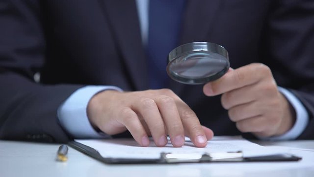 Attorney reading document with magnifier, studying case in detail, investigation