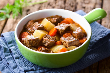 Fresh homemade beef stew with carrot and potatoes served in green bowl (Selective Focus, Focus one...